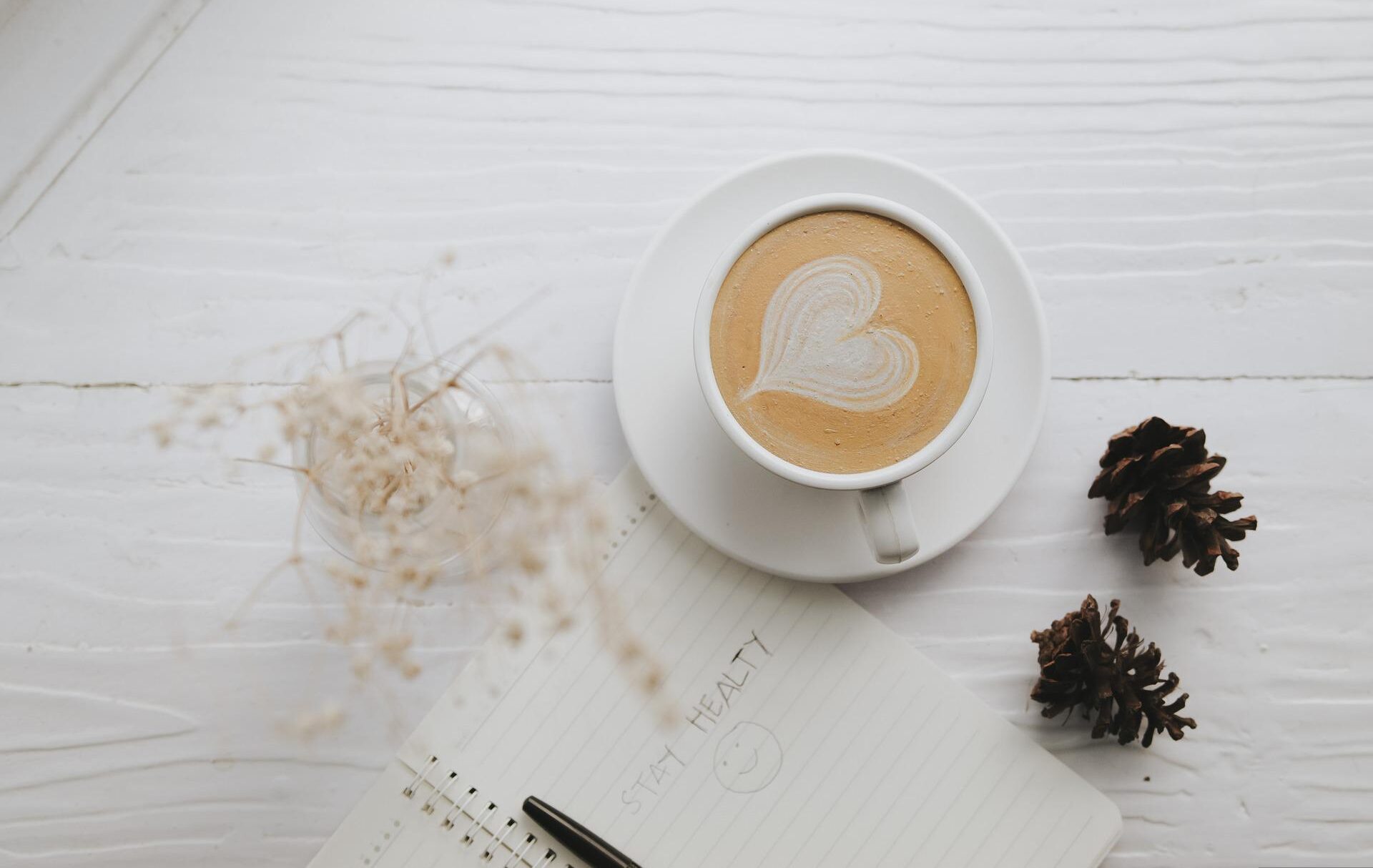 Image of coffee with a heart shape on a white desk next to a notebook - Sarah Richards Social
