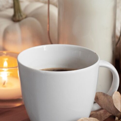 Image of a mug, candle and pumpkin. Autumn content