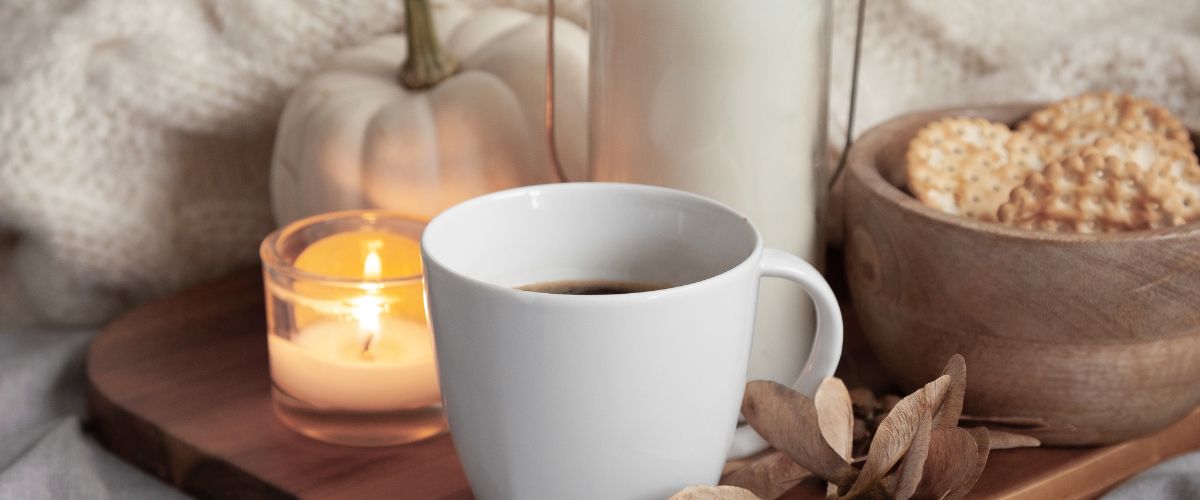 Image of a mug, candle and pumpkin. Autumn content