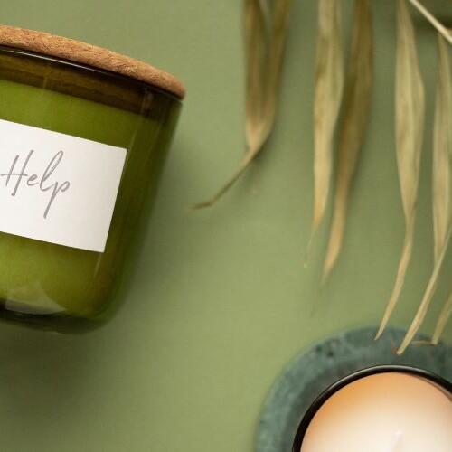 Image of a a candle with the word help and a palm leaf on a green background