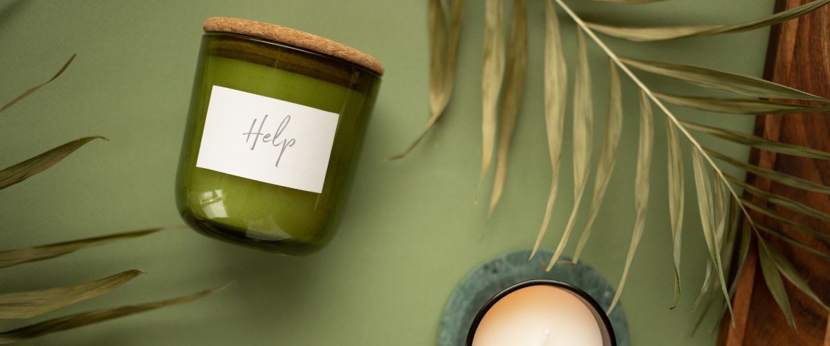 Image of a a candle with the word help and a palm leaf on a green background
