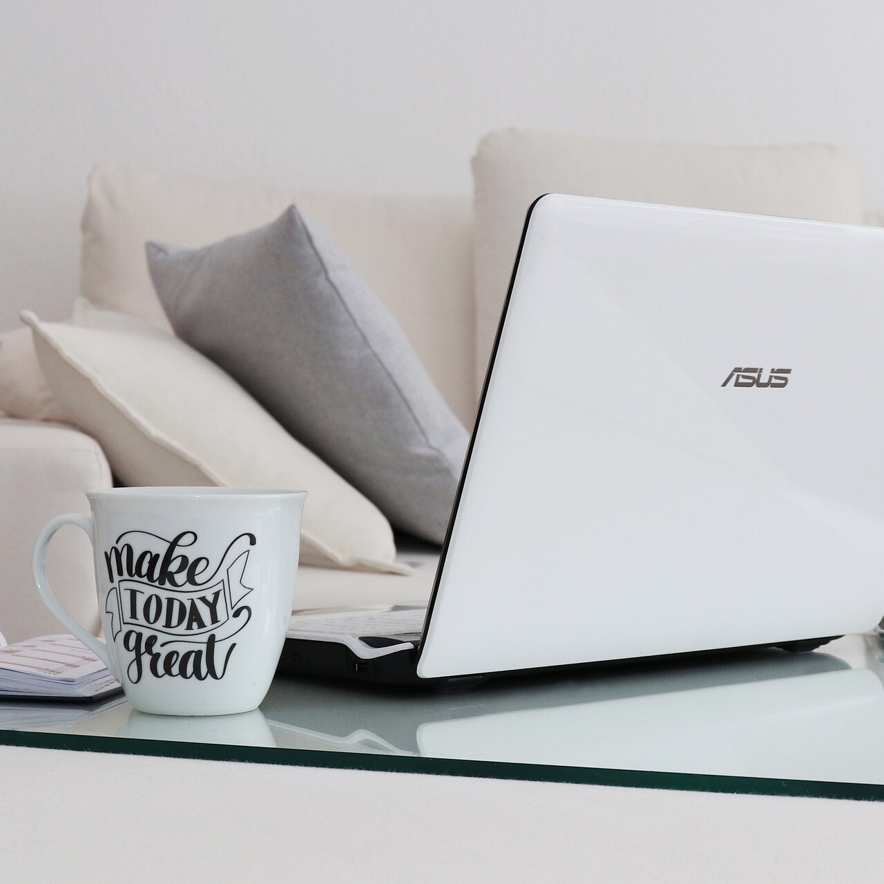 Laptop and big mug on coffee table, next to a cream sofa