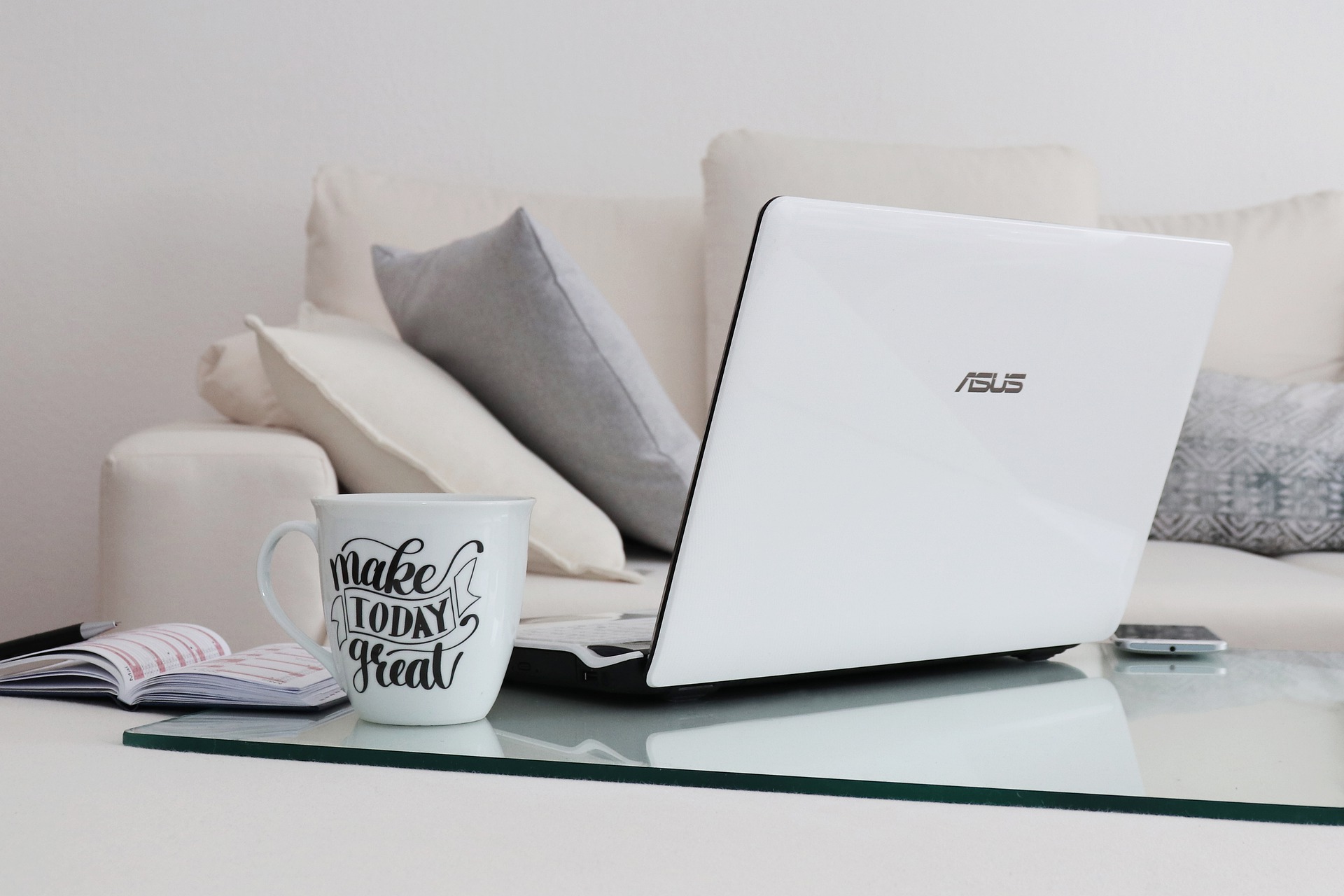 Laptop and big mug on coffee table, next to a cream sofa