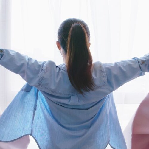 Image of woman opening her curtains widely - a let's do this action