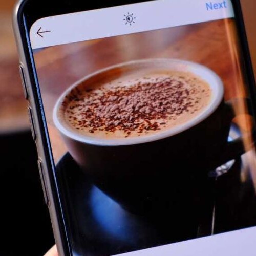 Image of a coffee and a phone taking a pic of it