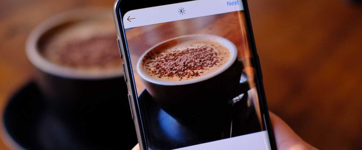 Image of a coffee and a phone taking a pic of it