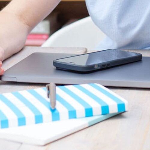 Image of a macbook, iphone and notebook on a desk