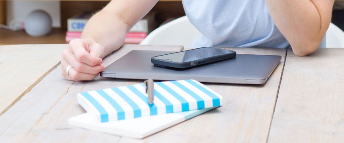 Image of a macbook, iphone and notebook on a desk
